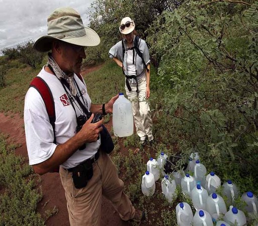 GREEN VALLEY, AZ - JULY 31: Volunteer Tim Doherty (L) inspects jugs of drinking water set out for immigrants crossing into Arizona from Mexico on a backcountry trail as fellow volunteer Rebecca Fowleron watches on July 31, 2010 near Green Valley, Arizona. Doherty conducts patrols for the non-profit Samaritans, delivering water to points near the U.S. Mexico border for immigrants crossing illegally into Arizona. He and fellow volunteers also provide medical assistance for distressed migrants, who often suffer from severe dehydration while crossing the desert. Immigrant aid groups and law enforcement alike say that the number of immigrants crossing illegally into Arizona from Mexico has slowed dramatically in 2010, with jobs scarce due to the U.S. recession and widespread fear in the Latino community associated with Arizona's new immigration enforcement law SB 1070. (Photo by John Moore/Getty Images) *** Local Caption *** Rebecca Fowlero;Tim Doherty