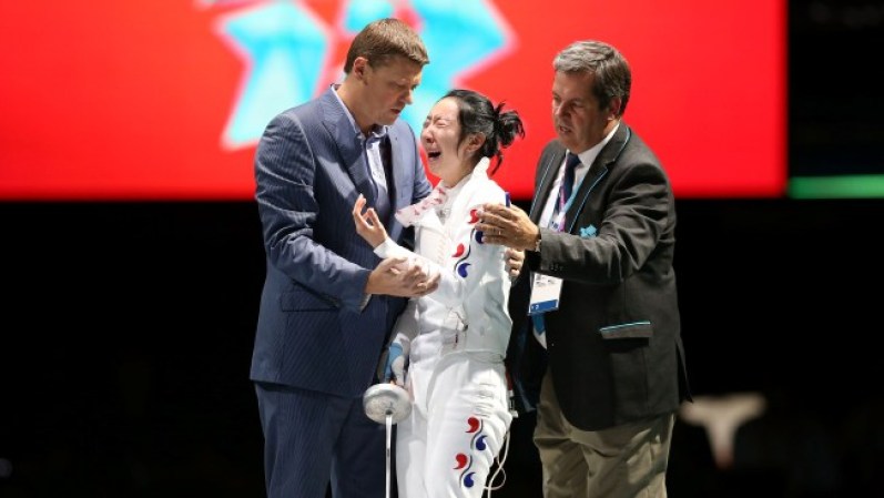 La esgrimista Shin A Lam de Corea del sur permanece casi una hora llorando durante la semifinal. La atleta se resistió a abandonar la pista y acusó a los jueces de haber perdido la medalla por un error del tablero.