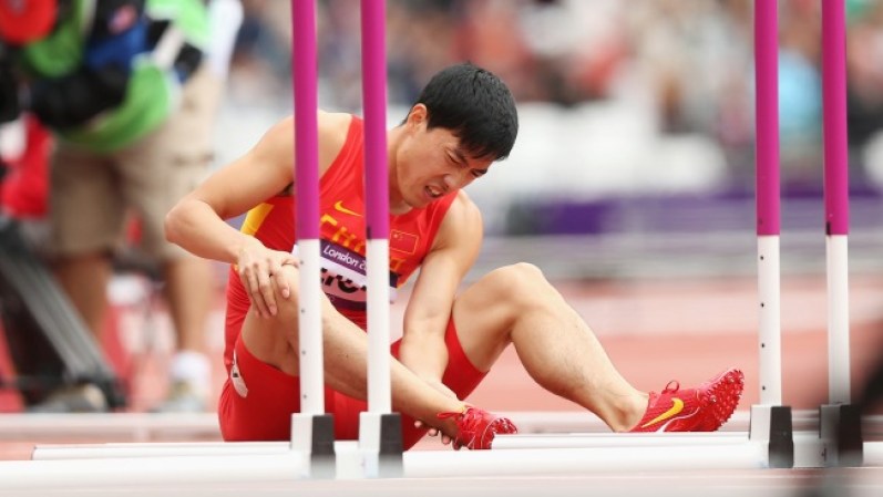 El atleta chino Liu Xiang, el gran favorito para la prueba de carrera con obstáculos cae en la primera valla y se queda en el suelo sin poder entender como el oro se le ha vuelto a escapar.