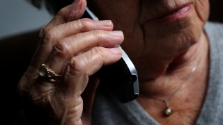 Una mujer mayor utiliza un teléfono fijo inalámbrico.