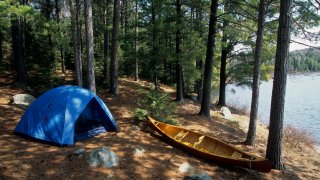 Canoeists camp with tent and canoe by the lake