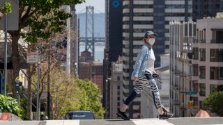 A pedestrian wearing a face masks crosses an empty street amid the coronavirus outbreak in San Francisco.