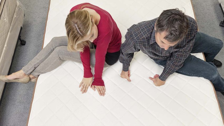 Friends sitting on mattress in furniture store