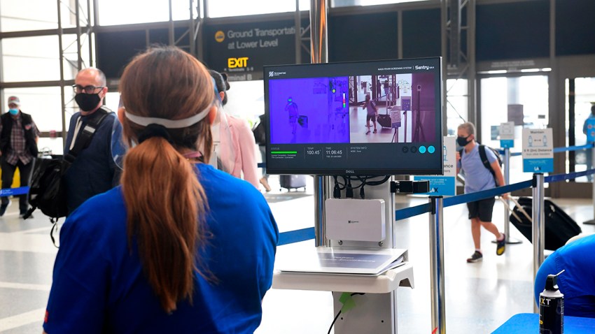Pasajeros en el Aeropuerto Internacional de Los Ángeles en Los Ángeles caminan frente a cámaras térmicas, este 23 de junio de 2020.
