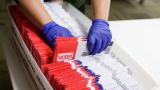 Election workers sort vote-by-mail ballots for the presidential primary