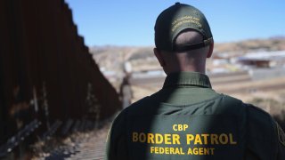 In this Feb. 26, 2013, file photo, a U.S. Border Patrol agent looks along a section of the recently-constructed fence at the U.S.-Mexico border in Nogales, Arizona.