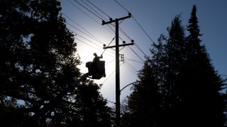 In this Oct. 15, 2020, file photo, PG&E line inspector Kevin Ogans works to clear lines so crews can begin removing a tree that crashed into live power lines along Mountain Boulevard in the Montclair Village neighborhood of Oakland, California.