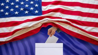 Una mano sale de una bandera de Estados Unidos y deposita un sobre lo deposita un papel en una urna de votación