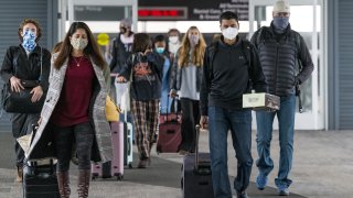 Travelers wearing protective masks arrive at San Francisco International Airport (SFO) in San Francisco, California, on Monday, Nov. 24, 2020. Airlines set a new post-pandemic record for U.S. passengers on Sunday as the Thanksgiving holiday spurred travel despite government warnings.