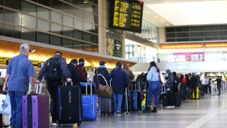 Travelers wait in line to check in for a flight