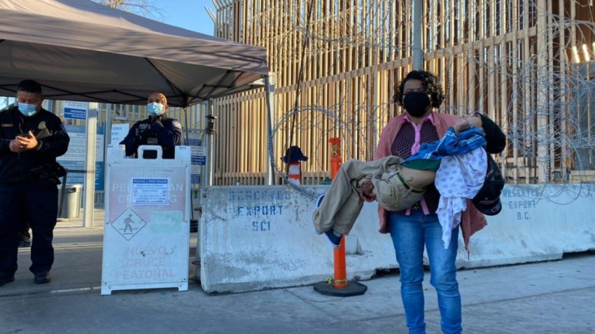 Migrante cruza la frontera con su hijo en brazos