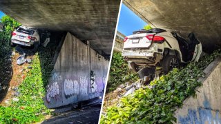 A Maserati wedged between an embankment and a freeway underside.