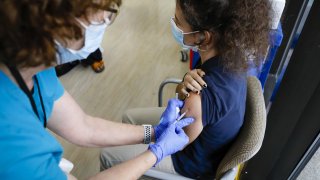 A health care worker administers a dose of the Pfizer-BioNTech Covid-19 vaccine to a teenager.