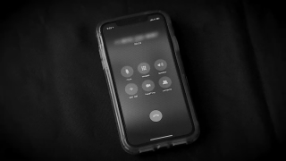An undated, black and white photo of an iPhone with a call in progress.