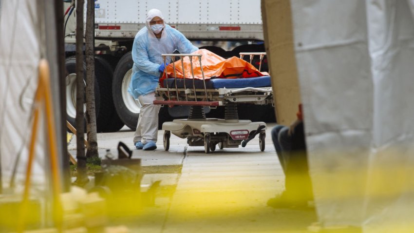 Bloomberg Best of the Year 2020: A medical worker in protective clothing moves the body of a deceased patient to a refrigerated overflow morgue outside the Wyckoff Heights Medical Center in Brooklyn, New York, U.S., on Friday, April 3, 2020. Photographer: Angus Mordant/Bloomberg via Getty Images