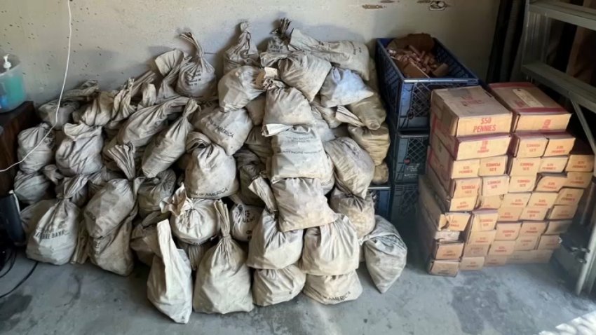 Bags and boxes of pennies stacked on a floor.