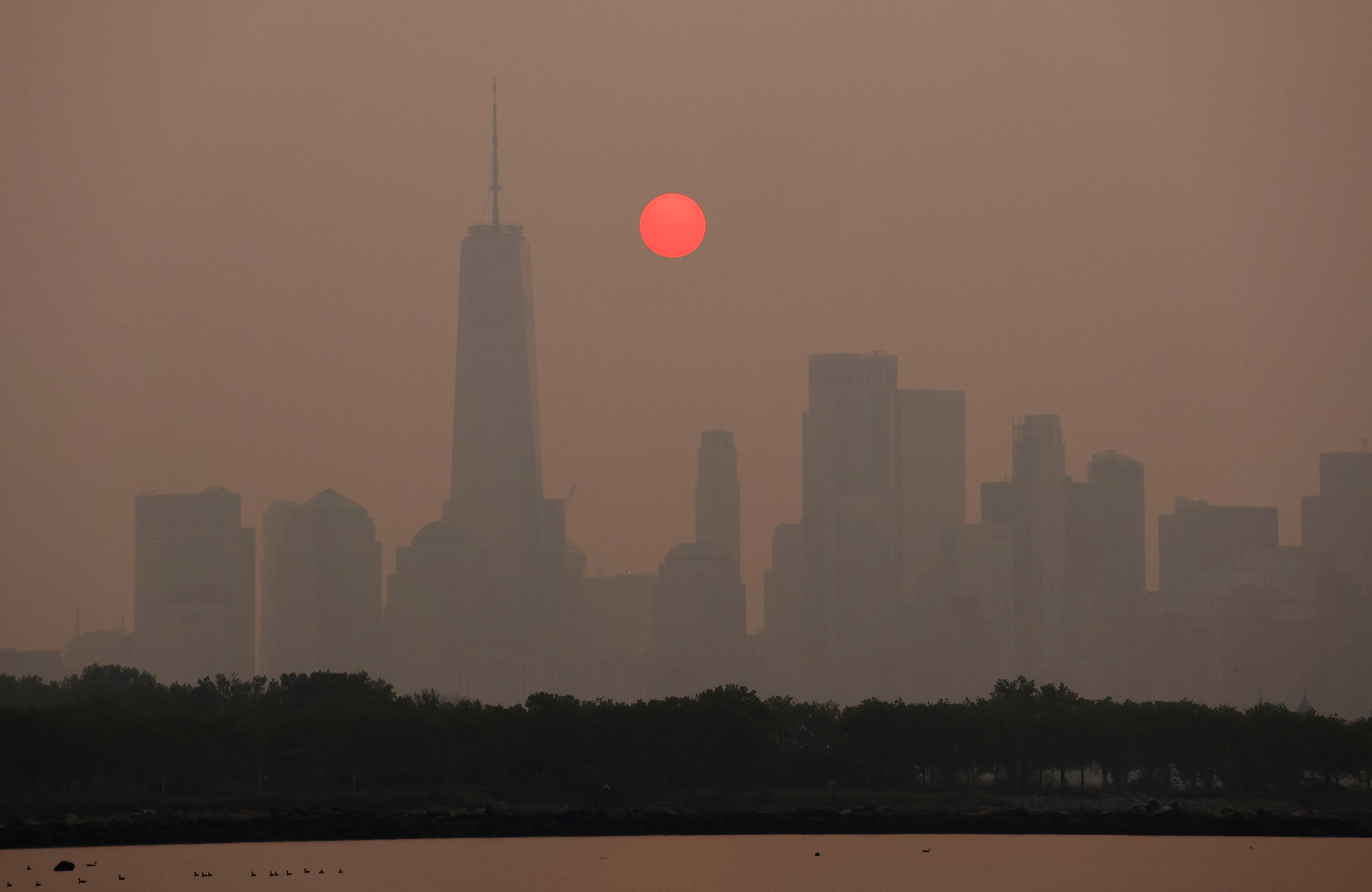 CIUDAD DE JERSEY, NJ – 7 DE JUNIO: El humo continúa envolviendo el sol a medida que se eleva detrás del horizonte del Bajo Manhattan y One World Trade Center en la ciudad de Nueva York el 7 de junio de 2023, visto desde la ciudad de Jersey, Nueva Jersey. (Foto de Gary Hershorn/Getty Images)