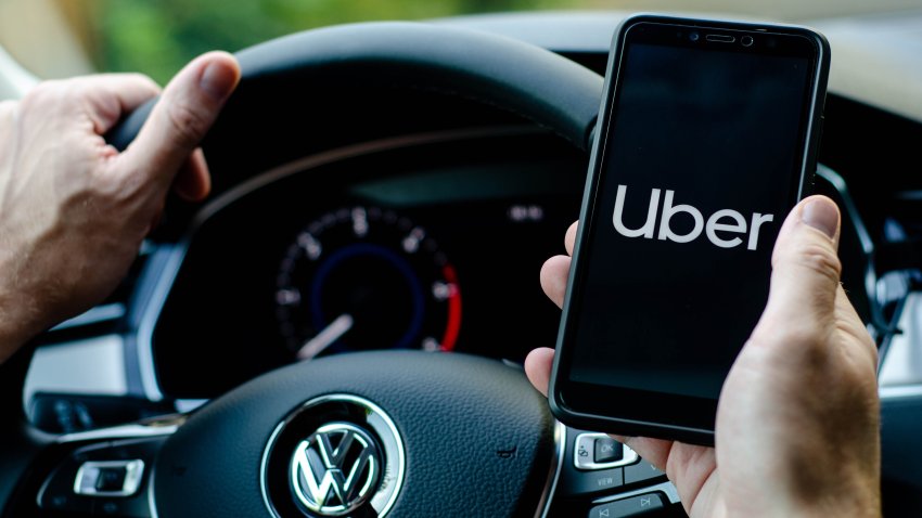 Soest, Germany – August 4, 2019: Uber driver holding smartphone in Volkswagen car. Uber is an American company offering transportation services online.