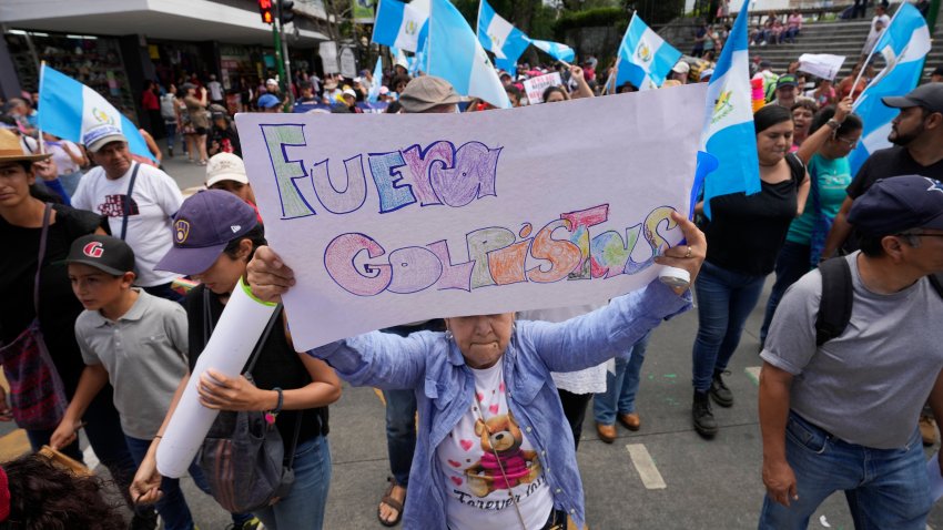 Una mujer sostiene un cartel con un mensaje que dice en español: “Fuera golpistas”, durante una marcha contra las acciones legales emprendidas por la Fiscalía General contra el partido Movimiento Semilla y el presidente electo Bernardo Arévalo en Ciudad de Guatemala, el sábado 2 de septiembre de 2023. (Foto AP/Moisés Castillo)