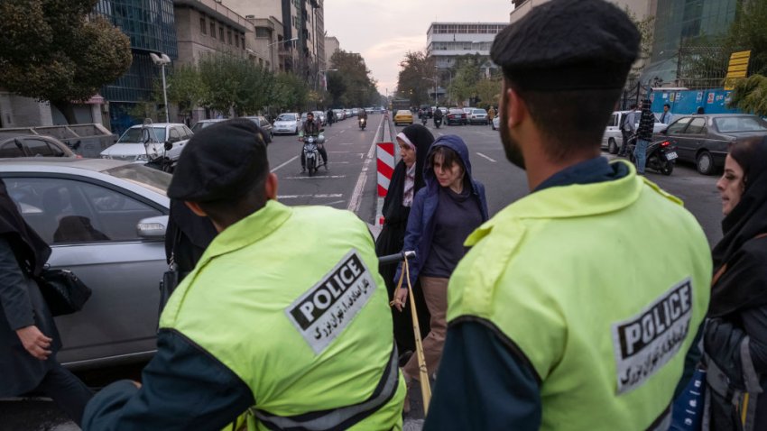 A young Iranian woman without wearing a mandatory headscarf, walks past an Iranian policeman in downtown Tehran, on November 13, 2023. (Photo by Morteza Nikoubazl/NurPhoto via Getty Images)