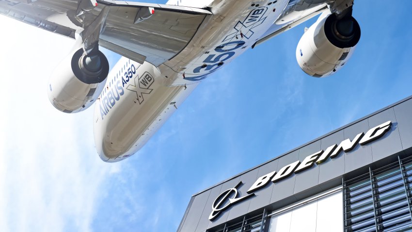 MOSCOW, RUSSIA – CIRCA AUGUST, 2015: Boeing company lettering logo against Airbus A350 modern airplane flying on blue sky background wide view usa europe competition trade war concept