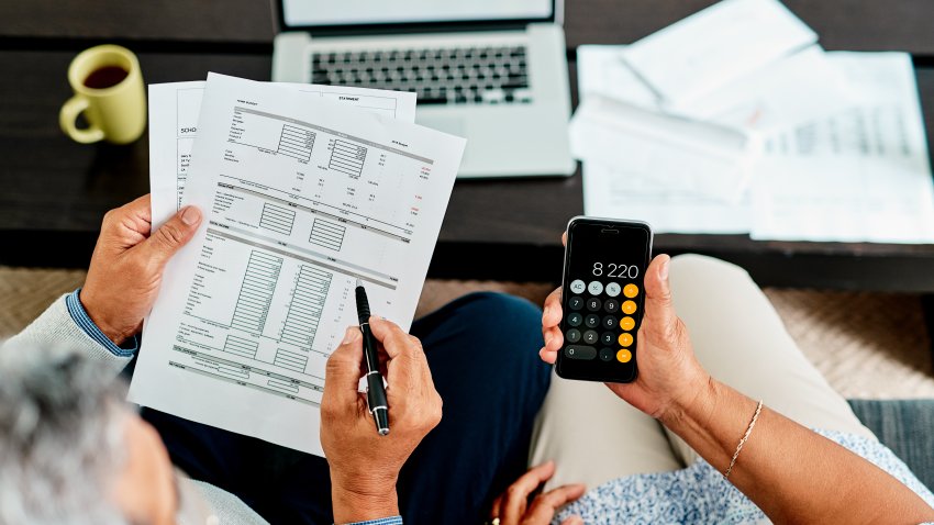 Toma desde un ángulo alto de una pareja calculando juntos sus finanzas en casa.