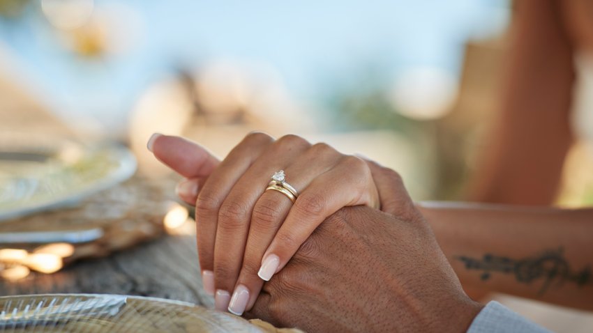 Bride with wedding ring holding hand of groom at table in winery