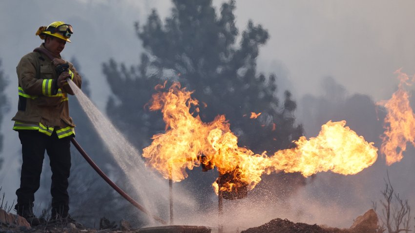 WRIGHTWOOD, CALIFORNIA – SEPTEMBER 11: A firefighter extinguishes a gas meter during the Bridge Fire which has now burned more than 47,000 acres in Angeles National Forest on September 11, 2024 in Wrightwood, California. Three large wildfires are currently burning in Southern California after igniting amid an intense heat wave in the region.  (Photo by Mario Tama/Getty Images)