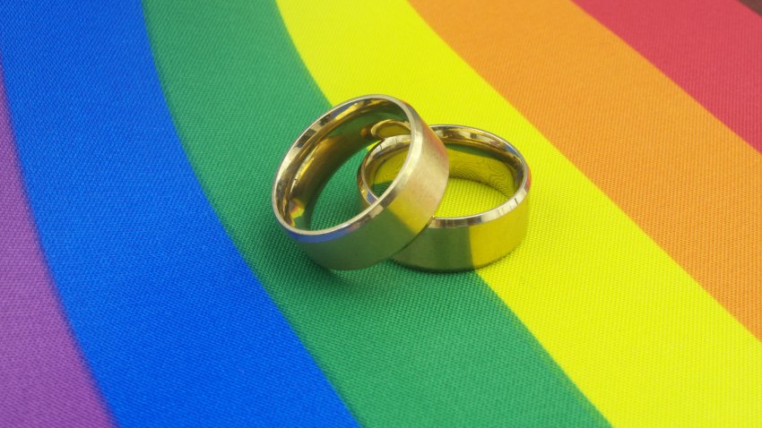 Gold wedding rings on LGBT pride flag. LGBT marriage concept.