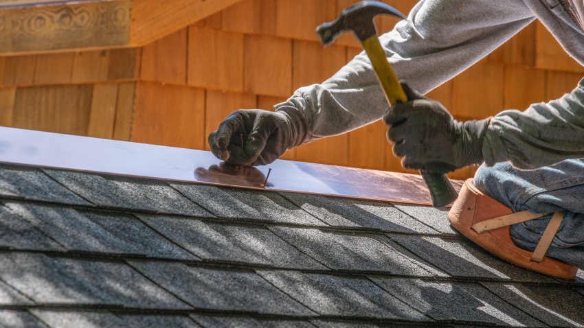 Installing new roof with  nail gun and shingles