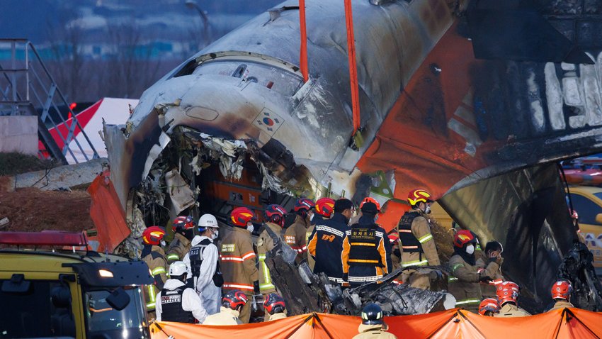 Resuce and inspection members in front of the wreckage of Jeju Air Co. Flight 2216 at Muan International Airport in Muan County, South Korea, on Sunday, Dec. 29, 2024. A Boeing Co. 737-800 aircraft operated by Jeju Air crashed and caught fire on an airport runway in South Korea, resulting in more than 170 people dead or missing. Photographer: SeongJoon Cho/Bloomberg via Getty Images