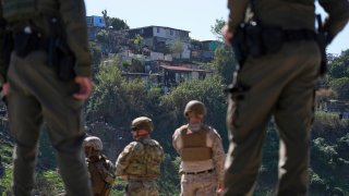 Agentes de la Patrulla Fronteriza y miembros del ejército miran hacia Tijuana, México, mientras se encuentran entre dos muros fronterizos, el 21 de marzo de 2025, en San Diego.