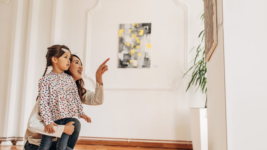 Mother and daughter in modern art gallery looking at paintings.