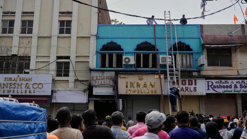 Gente  mirando mientras bomberos realizan tareas de rescate en un edificio tras un incendio en Hyderabad, India, el domingo 18 de mayo de 2025. (AP Foto/Mahesh Kumar A.)