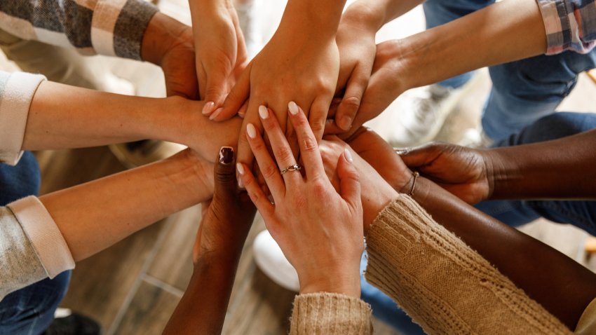 Directly above shot of unrecognizable group of diverse people holding hands stacked together after a successful group therapy session.